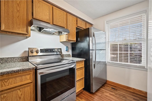 kitchen featuring under cabinet range hood, visible vents, light wood-style floors, appliances with stainless steel finishes, and brown cabinetry