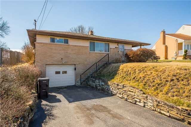 ranch-style house with aphalt driveway, an attached garage, brick siding, fence, and a chimney