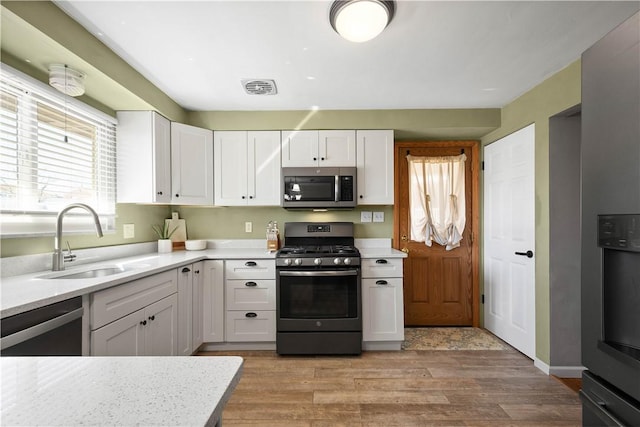 kitchen with light countertops, visible vents, appliances with stainless steel finishes, white cabinetry, and a sink