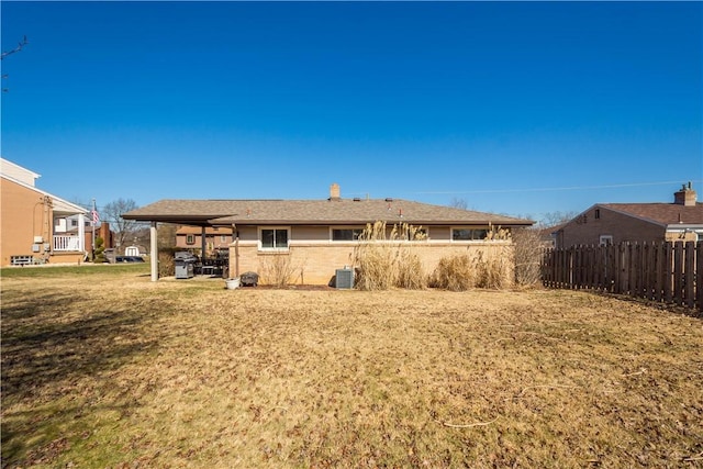 back of property with fence, cooling unit, and a yard