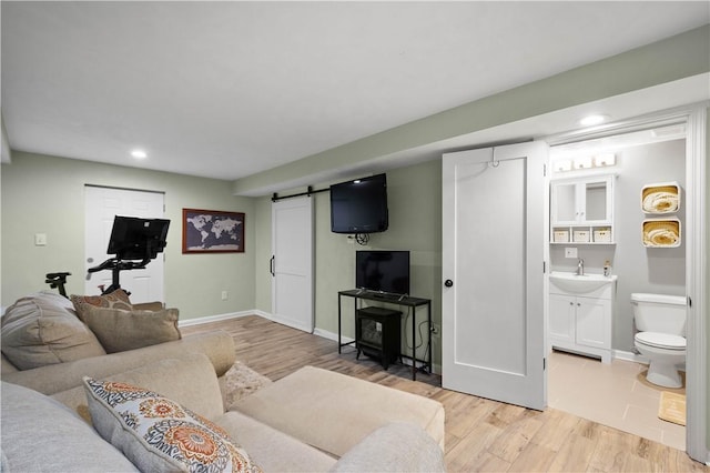 living area featuring recessed lighting, light wood-style flooring, baseboards, and a barn door