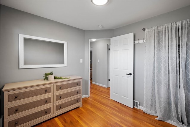 bedroom featuring light wood-type flooring, visible vents, and baseboards