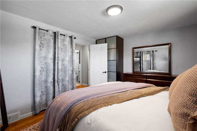 bedroom featuring baseboards, visible vents, and wood finished floors