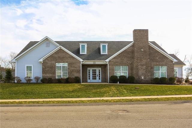 view of front of property featuring french doors, brick siding, a chimney, and a front yard