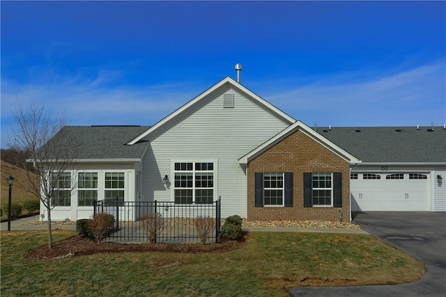 exterior space with brick siding, driveway, an attached garage, and a shingled roof