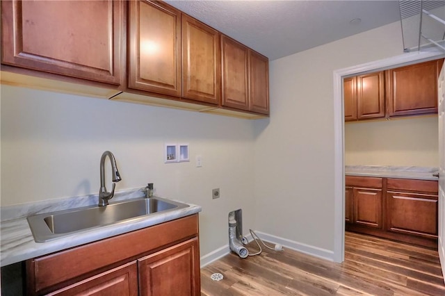 clothes washing area with washer hookup, wood finished floors, cabinet space, electric dryer hookup, and a sink