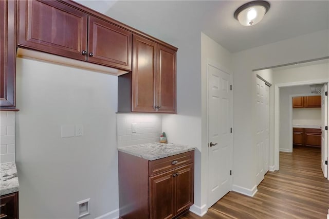 kitchen with light stone counters, dark wood-style floors, and decorative backsplash