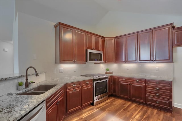 kitchen featuring lofted ceiling, dark wood-style flooring, a sink, stainless steel appliances, and reddish brown cabinets