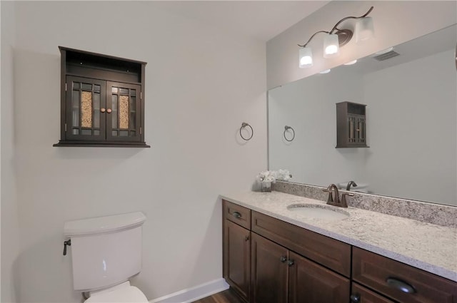 bathroom with visible vents, toilet, vanity, and baseboards