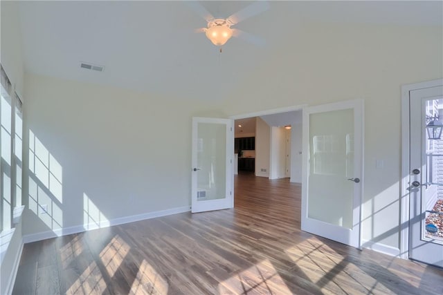 unfurnished room with visible vents, baseboards, french doors, a high ceiling, and wood finished floors