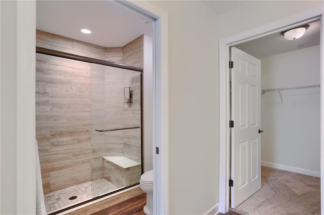 full bathroom featuring a shower stall, a spacious closet, toilet, and baseboards