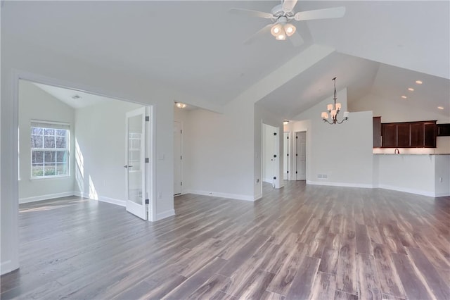 unfurnished living room with ceiling fan with notable chandelier, baseboards, lofted ceiling, and wood finished floors