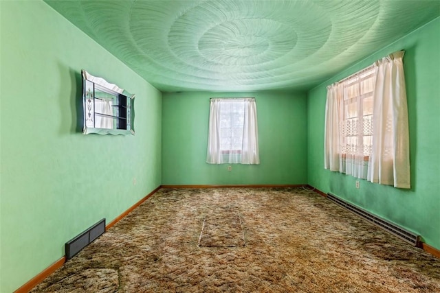 carpeted empty room featuring a baseboard radiator, a textured ceiling, visible vents, and baseboards