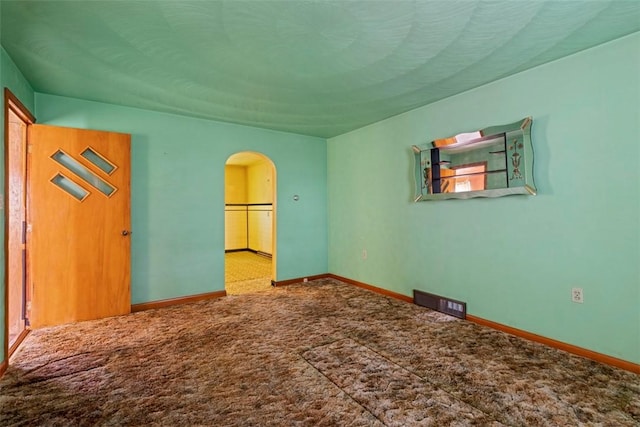 unfurnished bedroom featuring carpet floors, visible vents, baseboards, and arched walkways