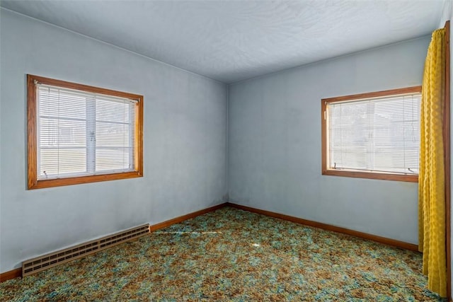 carpeted empty room featuring baseboards and baseboard heating