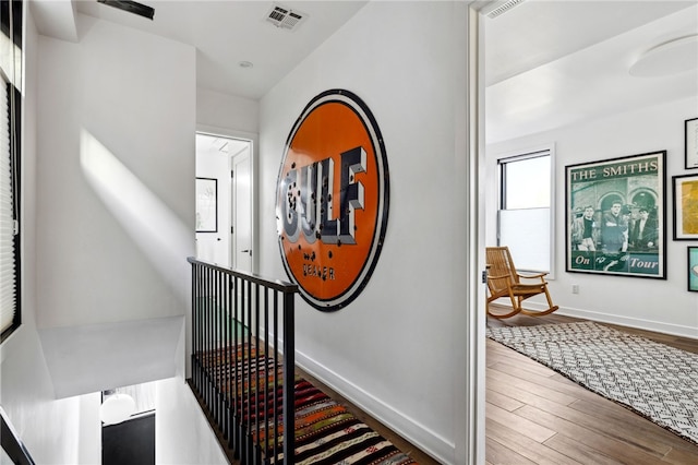 hall featuring visible vents, baseboards, and wood finished floors