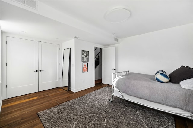 bedroom with a closet, wood finished floors, visible vents, and baseboards