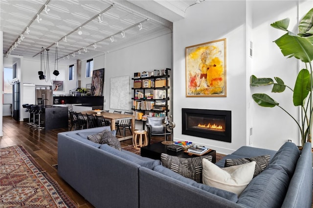 living room featuring dark wood-style floors, track lighting, and a glass covered fireplace