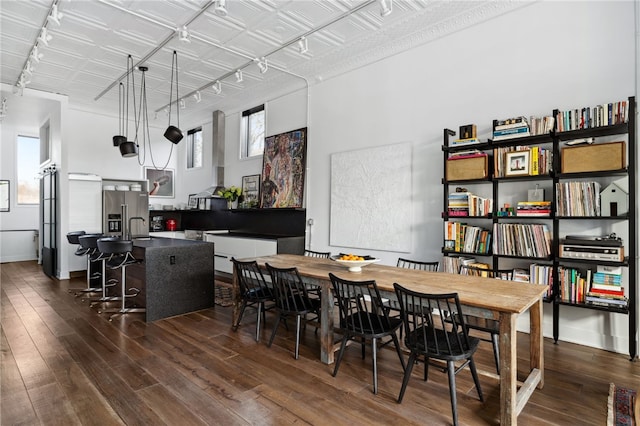 dining space featuring baseboards, dark wood-style flooring, an ornate ceiling, and track lighting