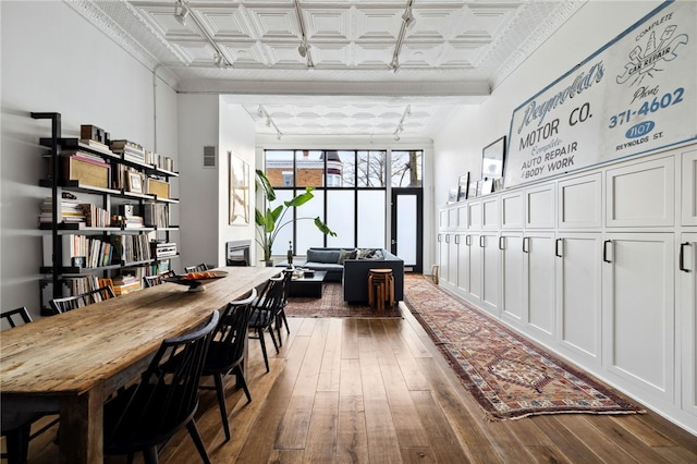 interior space featuring an ornate ceiling, rail lighting, visible vents, expansive windows, and hardwood / wood-style floors