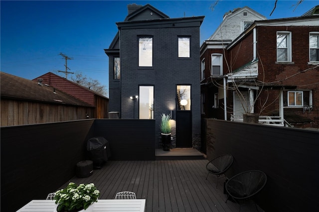 rear view of house with brick siding and a wooden deck