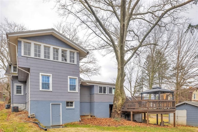 back of property featuring an outbuilding, central air condition unit, a storage unit, a gazebo, and a wooden deck