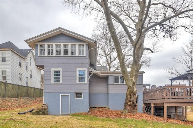 back of property featuring a deck, a yard, and fence