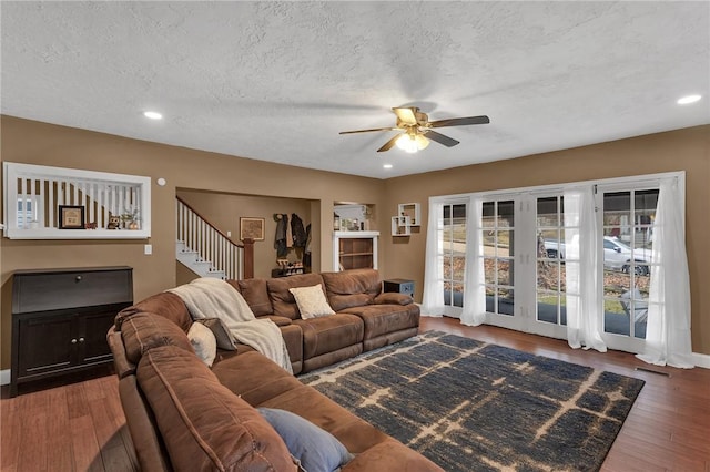 living area featuring a textured ceiling, ceiling fan, recessed lighting, wood finished floors, and stairs