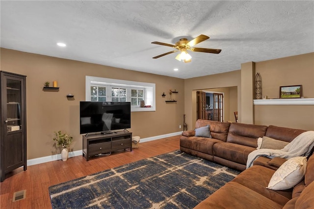 living room with visible vents, baseboards, and wood finished floors