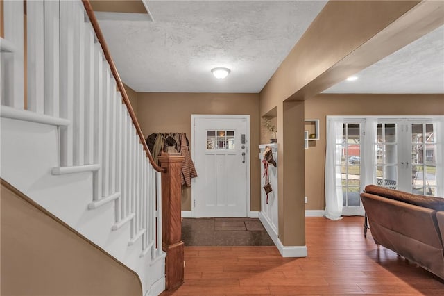 entrance foyer with a textured ceiling, baseboards, french doors, stairway, and wood-type flooring