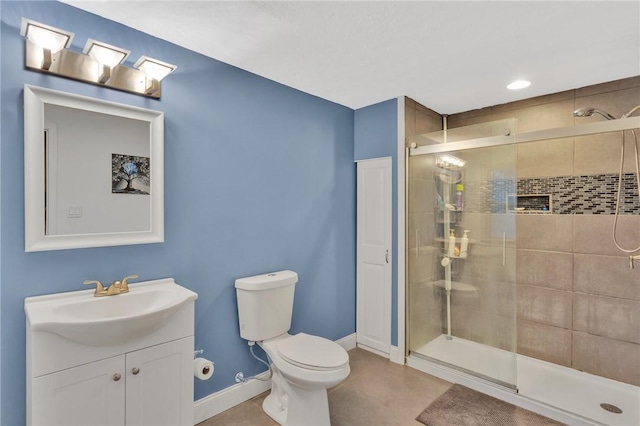 bathroom featuring baseboards, a shower stall, toilet, and vanity