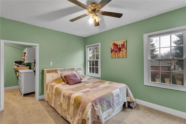 bedroom with carpet, a spacious closet, baseboards, and ceiling fan