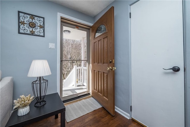 foyer with dark wood-style floors and baseboards