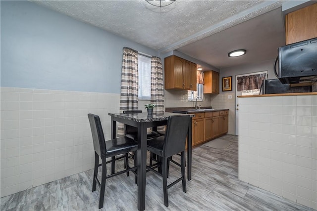 kitchen with dark countertops, brown cabinets, a sink, and tile walls