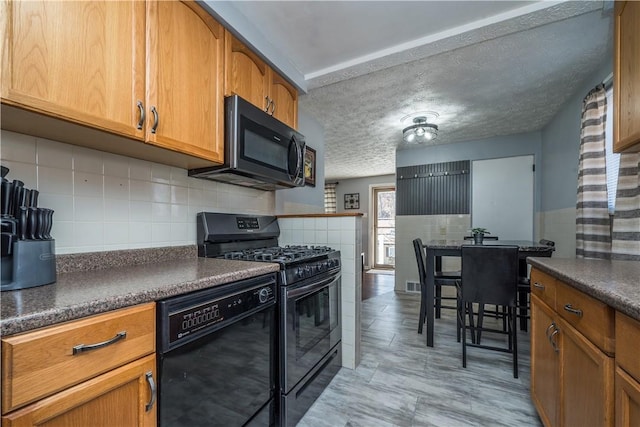 kitchen with a textured ceiling, visible vents, brown cabinets, black appliances, and dark countertops