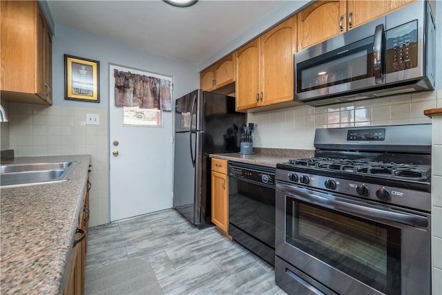 kitchen featuring appliances with stainless steel finishes, brown cabinetry, a sink, and tasteful backsplash