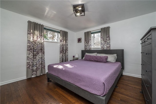 bedroom featuring multiple windows, baseboards, and wood finished floors