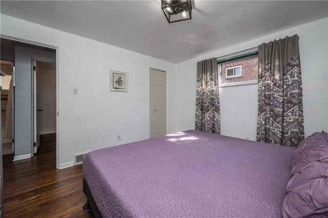 bedroom with baseboards, visible vents, and wood finished floors