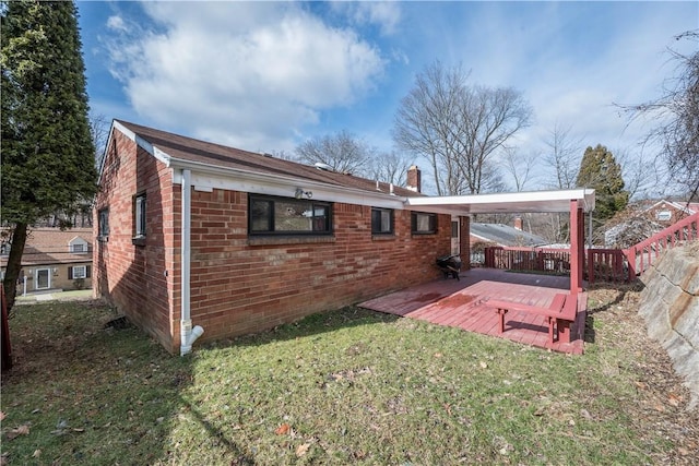 back of property featuring a yard, brick siding, a chimney, and fence