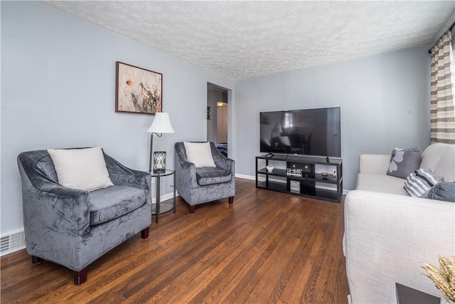 living room with visible vents, a textured ceiling, baseboards, and wood finished floors