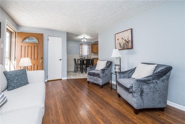 living area featuring dark wood-style floors, a healthy amount of sunlight, a textured ceiling, and baseboards