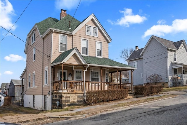 view of front of house featuring covered porch, roof with shingles, and a chimney