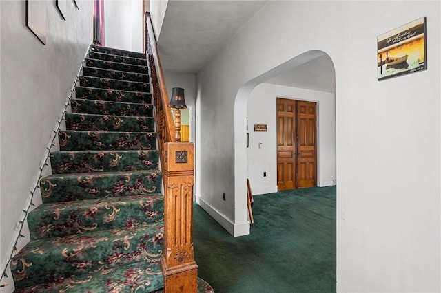 stairs featuring arched walkways, carpet, and baseboards