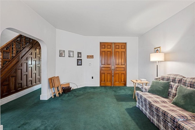 sitting room with arched walkways, carpet flooring, baseboards, and stairs