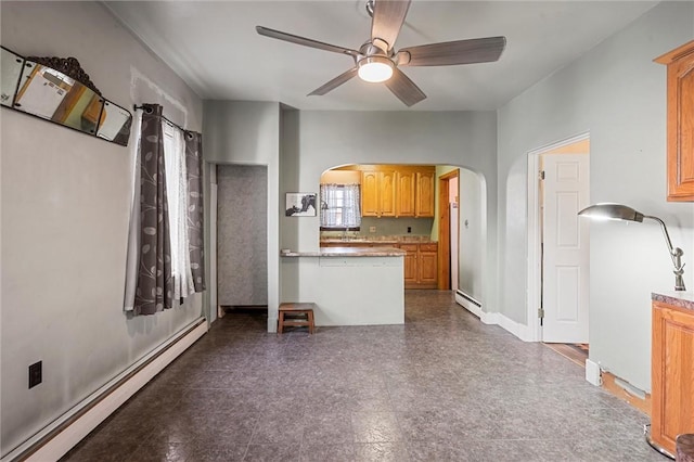 kitchen featuring a baseboard heating unit, ceiling fan, arched walkways, and baseboards