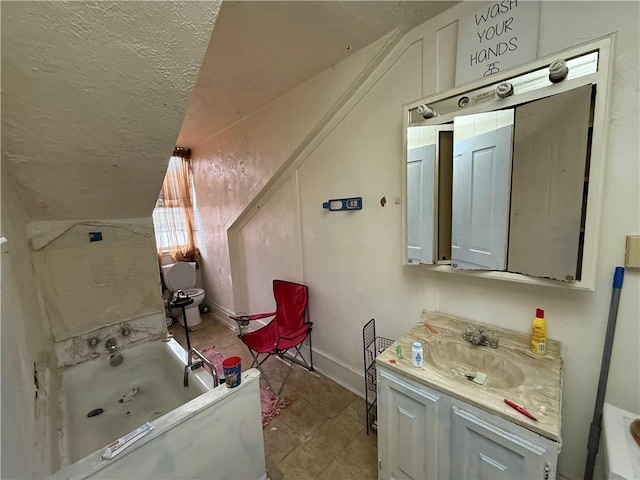 full bath with a textured ceiling, vanity, baseboards, and a bathing tub