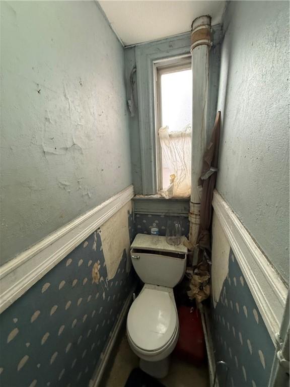 bathroom with toilet and a wainscoted wall