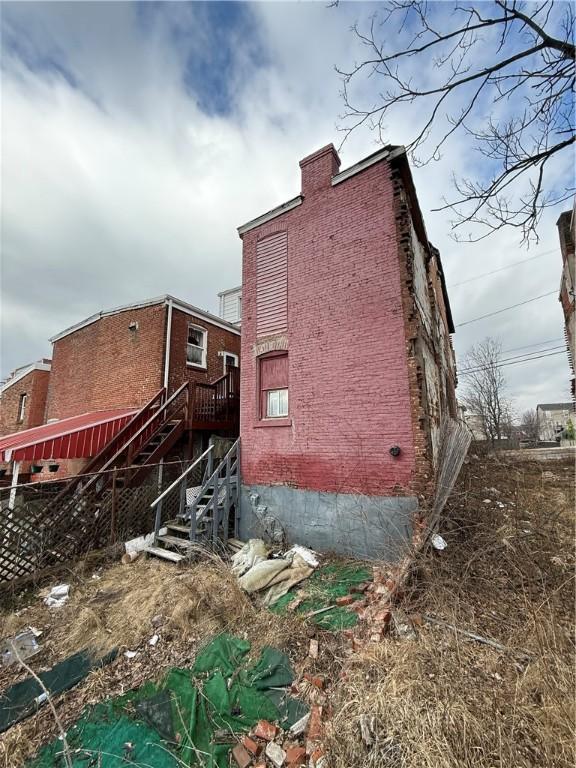 view of property exterior featuring brick siding and stairway