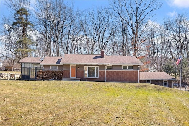 single story home with a sunroom, brick siding, a chimney, and a front lawn