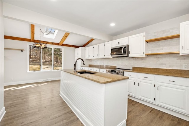 kitchen featuring stainless steel appliances, backsplash, light wood-style flooring, lofted ceiling with skylight, and a sink